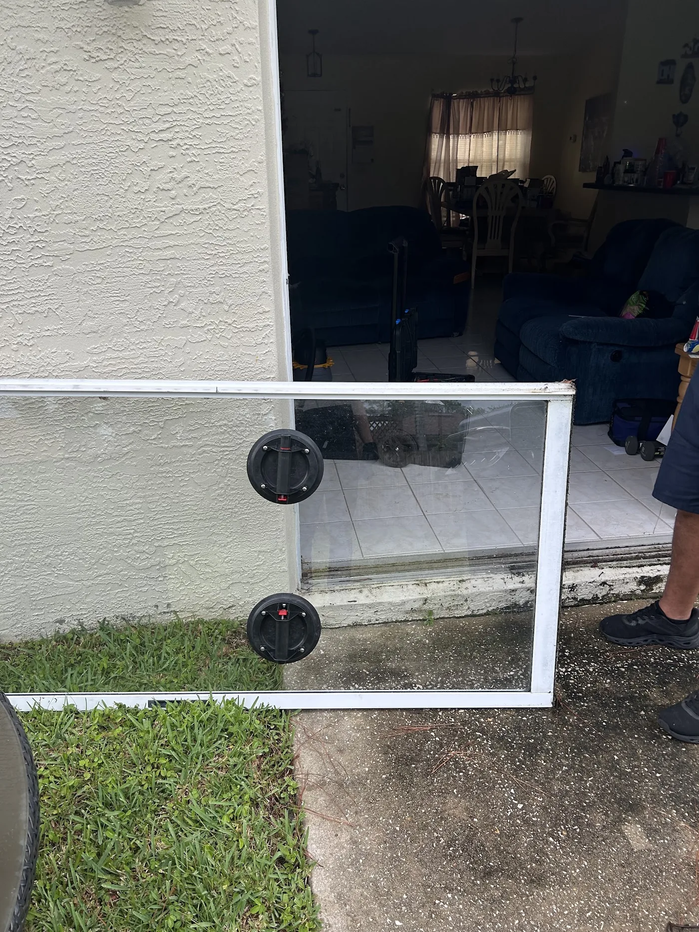 Technician removing a sliding door glass panel with suction cups for glass replacement