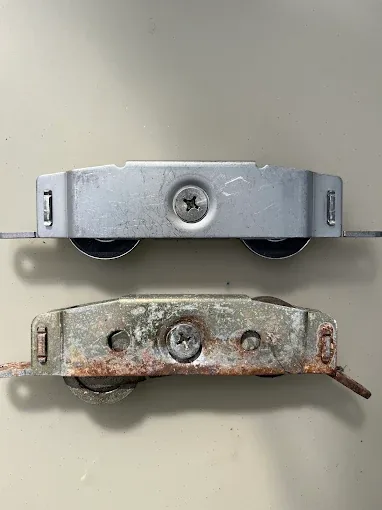 New stainless sliding door roller beside a corroded worn-out roller