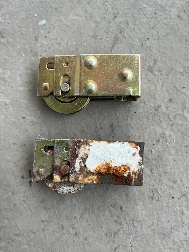 Corroded original sliding door roller next to a new replacement roller