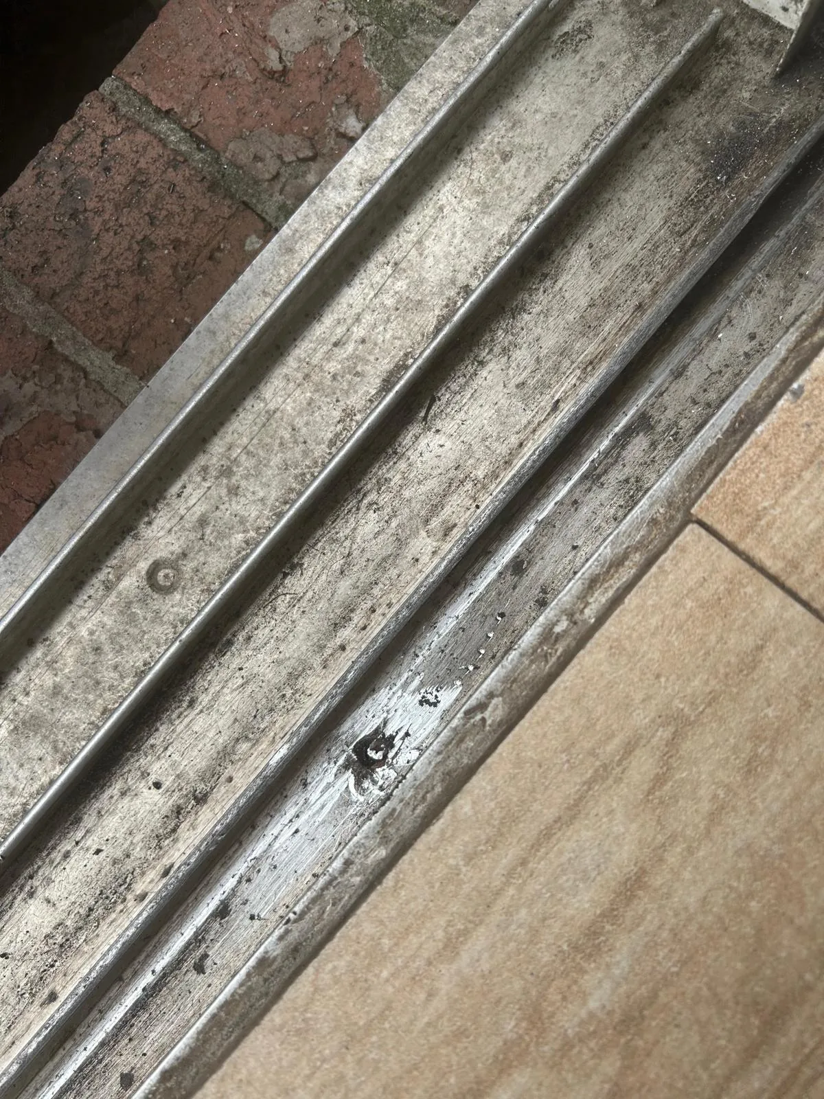 Worn aluminum sliding door track rail before repair